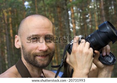 Cheerful smiling photographer in a forest in a sunny day. Close-up