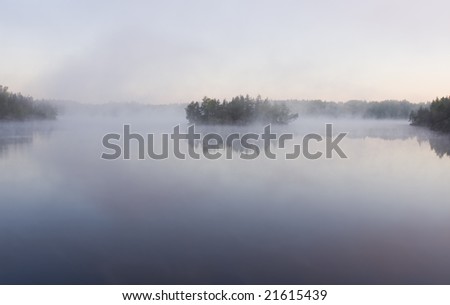 Islands in morning fog on wild forest lake in Karelia
