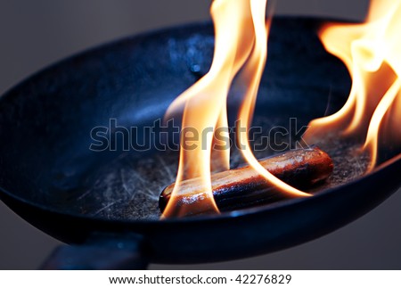danger cooking, sausage in the flame in frying pan