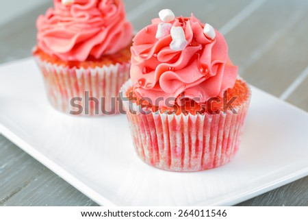 Two cupcakes with strawberry over white font