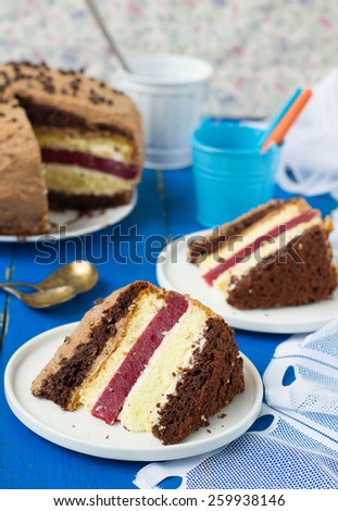 Biscuit cake with vanilla and chocolate cream and cherry jelly