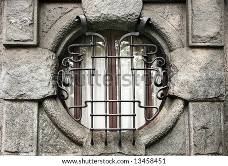Round window with metal bars in the old house. Milan. Italy.