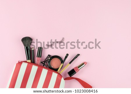 Make up bag with various cosmetics and brushes isolated on pink background, Top view, Beauty concept