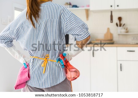 Tired young woman standing at kitchen room with cleaning products and equipment, Housework concept