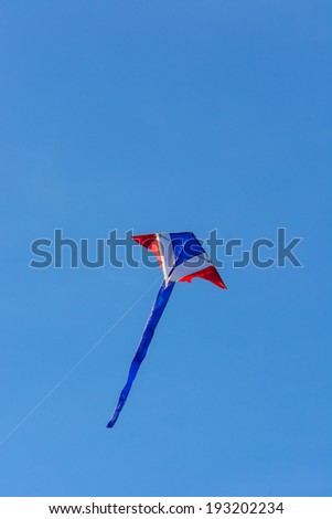 A kite string leads to a kite flying with a clear blue sky background.