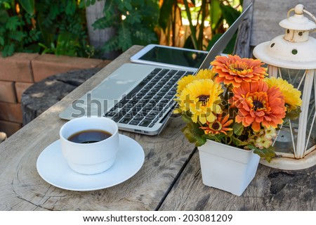 a cup of coffee and laptop on wood floor with flower