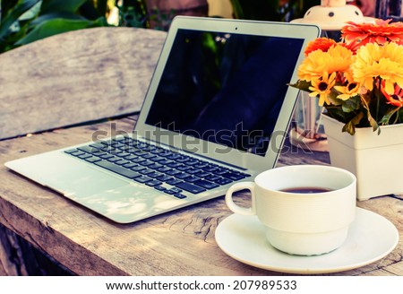 a cup of coffee and laptop on wood floor with flower, vintage style