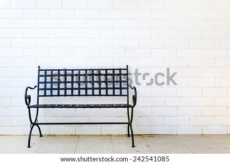 Black metal bench with white brick wall