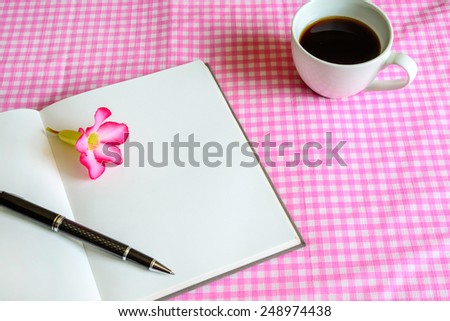 Blank note book with cup of coffee and flower with shadow