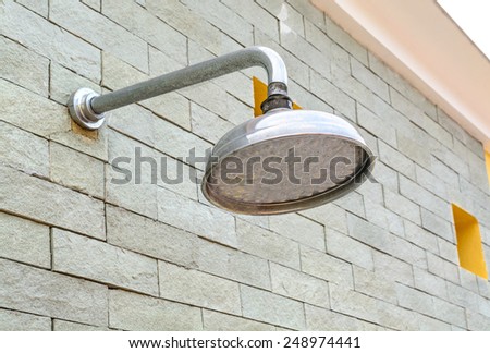 Outdoor shower head at swimming pool with brick wall