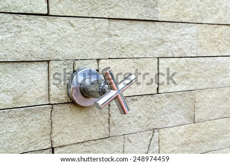 Outdoor shower head at swimming pool with brick wall