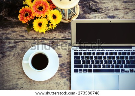 a cup of coffee and laptop on wood floor with flower, vintage style