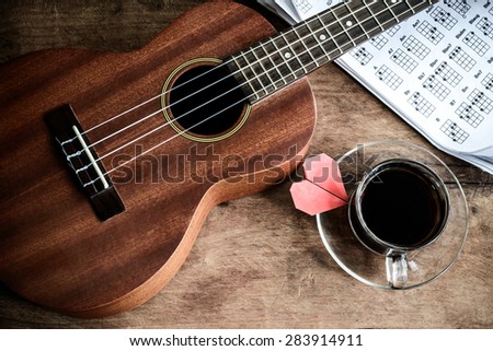 cup of coffee and ukulele on old wooden background, Dark tone