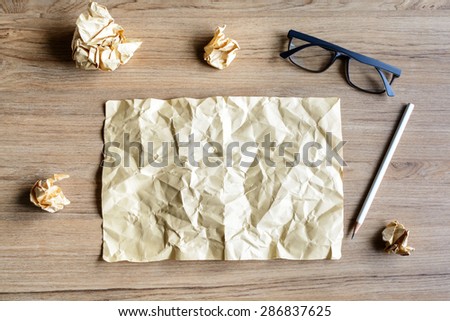 Crumpled paper balls with eye glasses on wood desk, creative writing concept