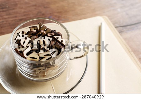 Wooden letter in a cup of coffee with book on old wooden background, Education concept