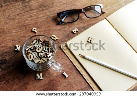 Wooden letter in a cup of coffee with book on old wooden background with soft light, Education concept
