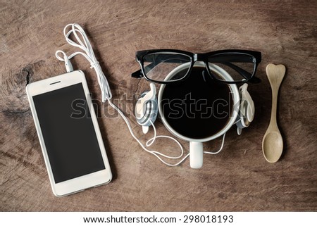 Cup of coffee with earphone and cellphone on wooden background, Sepia tone