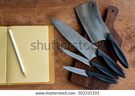 Set of kitchen knifes on wooden cutting board on old wooden table