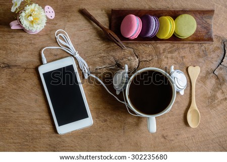 Colorful macaroons and a cup of coffee with cellphone on wooden table
