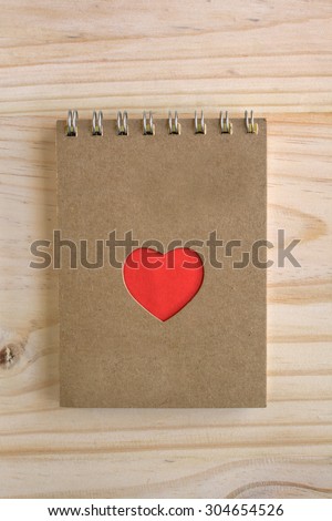 Recycle notebook with red heart shape on wooden desk, conservation concept