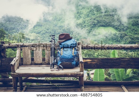 Travel backpack on the wooden bench with landscape view of mountain and fog