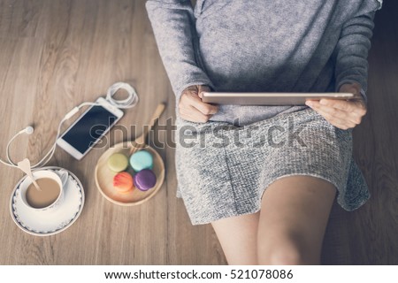 Young woman relaxing at cozy home atmosphere on the wooden floor with cup of coffee and macaroon.