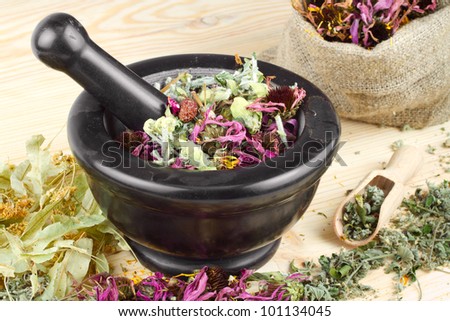mortar and pestle and sack with healing herbs on wooden table