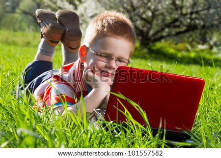 boy using his laptop outdoor in park on grass