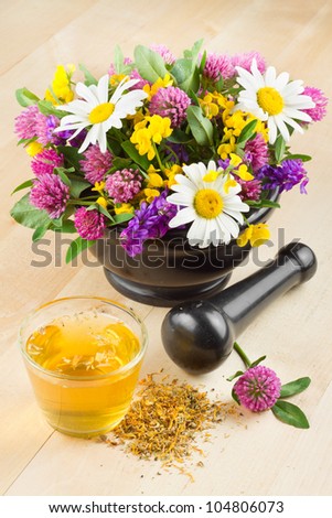 mortar with healing herbs and flowers, herbal tea on table, alternative medicine