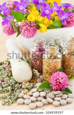 different healing herbs in glass bottles, flowers bouquet in mortar, tablets, herbal medicine