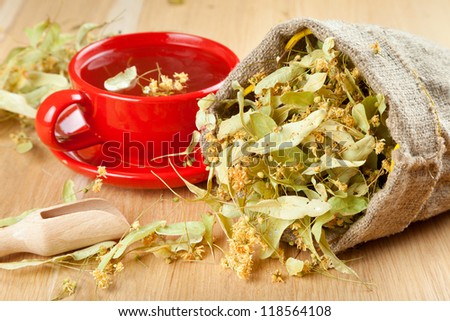 cup of linden tea and flowers in canvas bag on wooden table