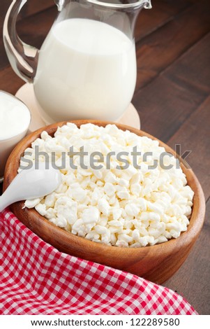 cottage cheese in rustic wooden plate and Glass jug with milk, sour cream