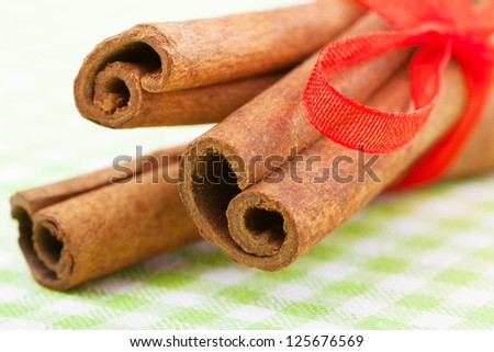 cinnamon sticks with red ribbon on green tablecloth