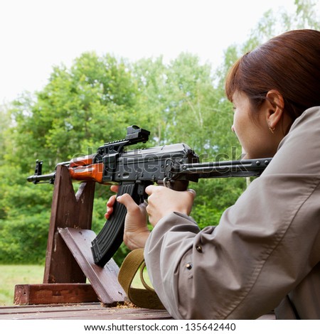 young woman shooting an automatic rifle for strike ball