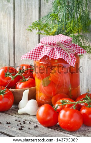 Homemade tomatoes preserves in glass jar. Fresh and canned tomatoes on wooden board
