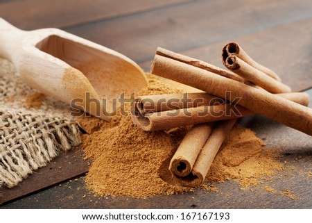 Cinnamon sticks and cinnamon powder in wooden scoop, on table