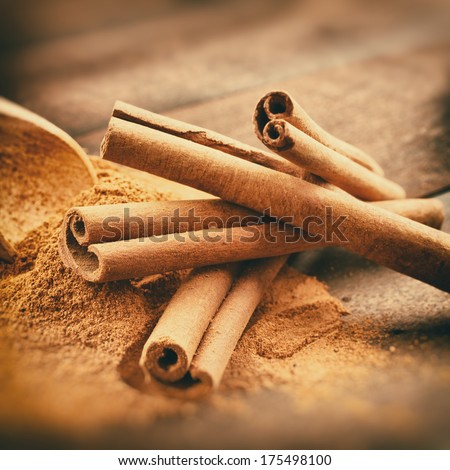 Vintage stylized photo of Cinnamon sticks and cinnamon powder on wooden plank