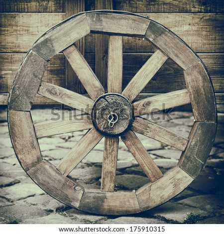 Vintage stylized photo of wooden cart wheel on stone road