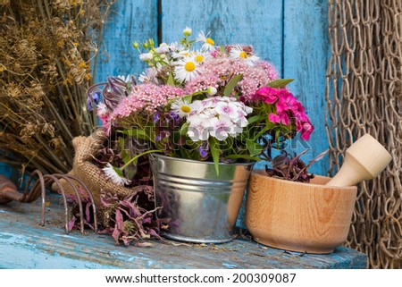 garden flowers in bucket and mortar with healing herbs