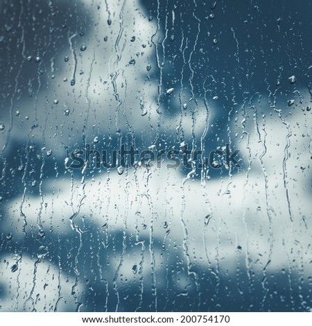 rain Drops and flows on window, blue sky with clouds on background