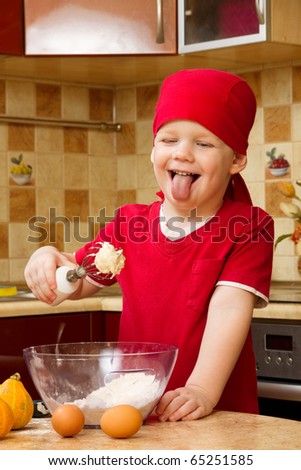 Small boy helping at kitchen with baking a pie, little chef
