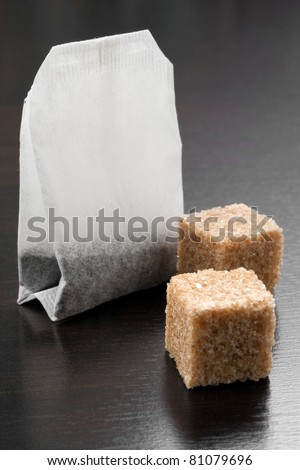 tea bag with lumps of sugar on black table