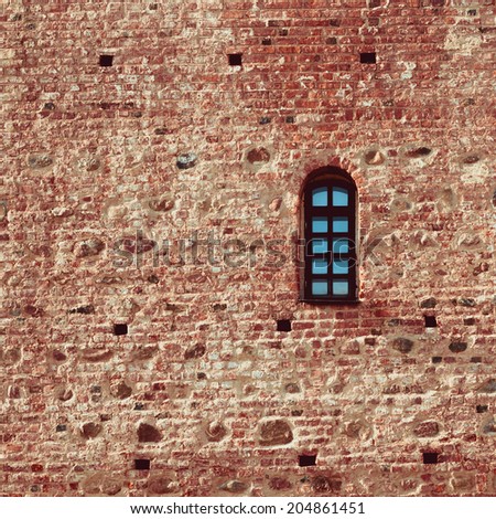 small arched window in a aged red brick castle wall