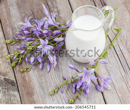 Milk jug and bluebell flowers bunch on wooden rustic table