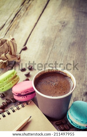 macaroons, espresso coffee cup and sketch book on wooden rustic table, vintage stylized photo