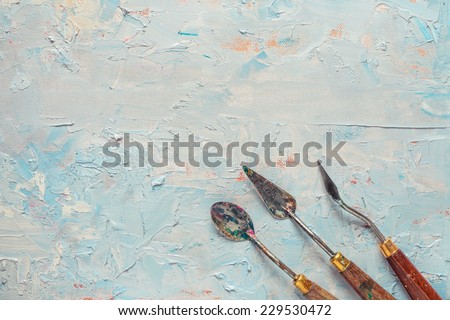 three palette knifes on artist canvas with coating of oil paint