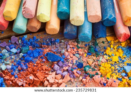 Collection of rainbow colored pastel crayons with crushed chalk closeup on desk. .