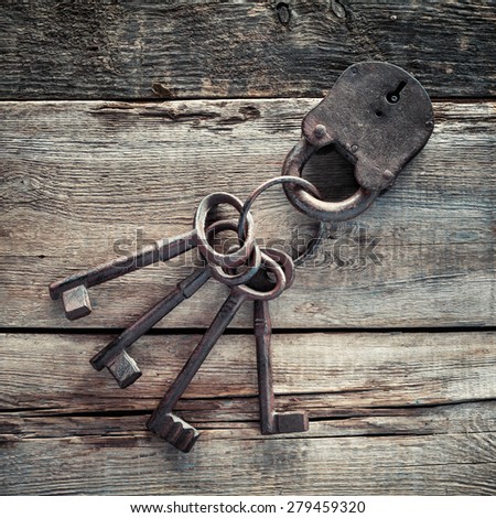 Old rusty lock with keys on wooden background.