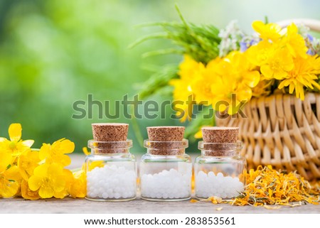 Bottles of homeopathy globules and healthy herbs in wicker basket.