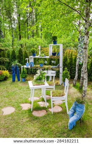Minsk, Belarus, 23-May-2015: Garden composition -  bookshelf with books and potted plants, table and chairs, figures from jeans on holiday in nursery \